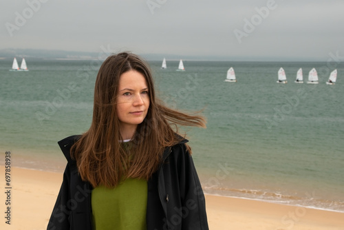 Young woman on the beach with windsurfers in the background