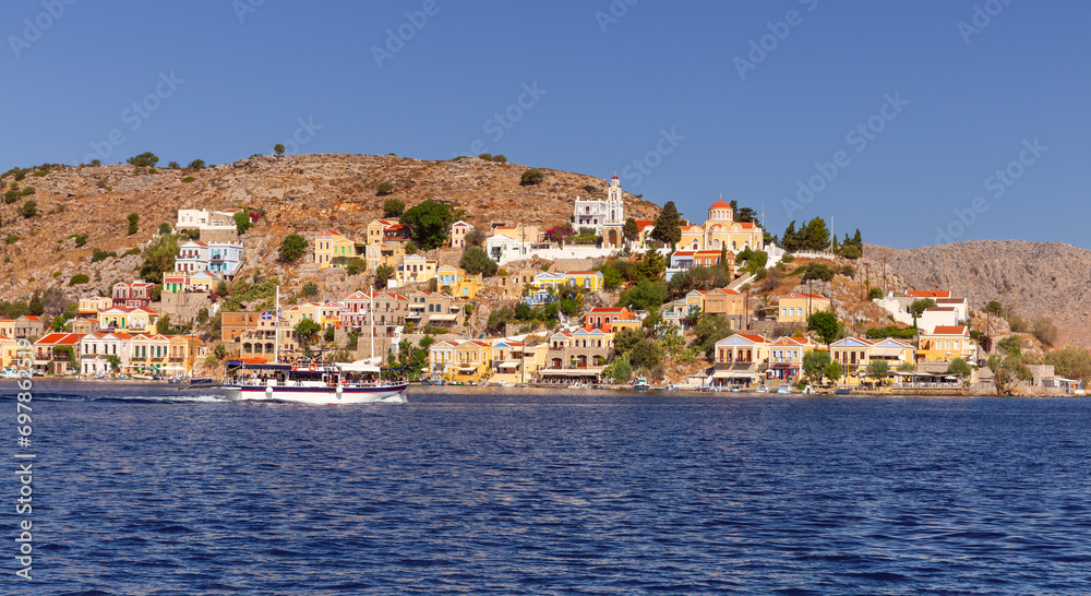 Multi-colored facades of houses in the village Symi on a sunny day.