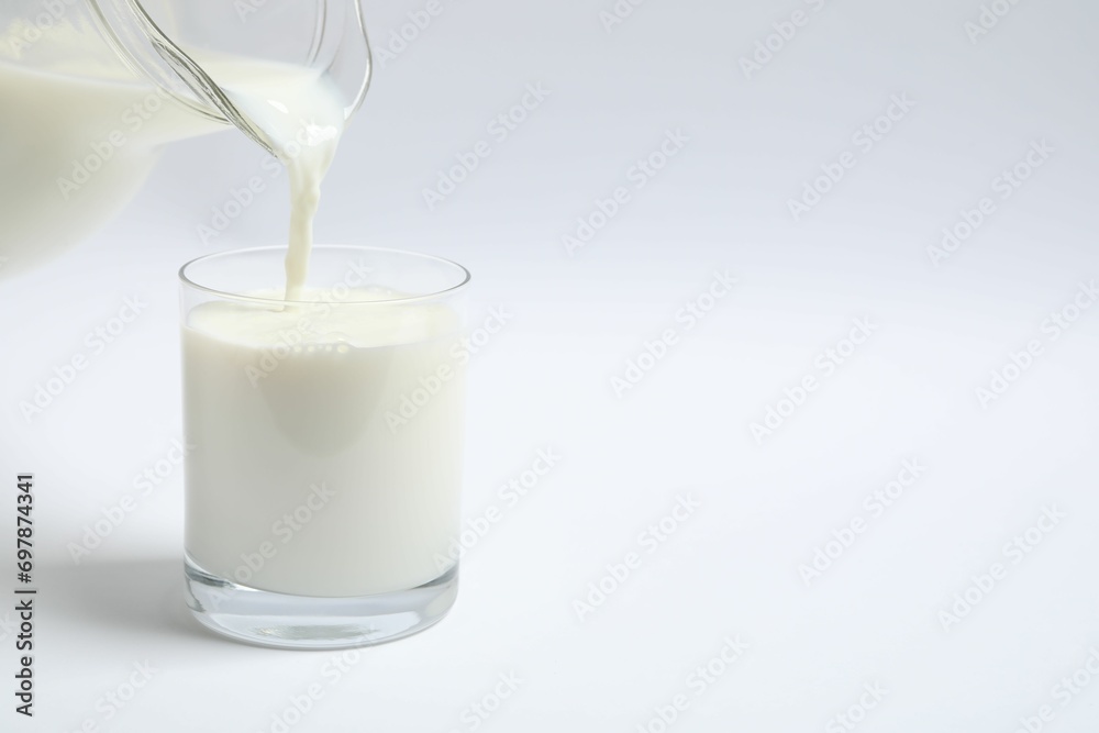 Pouring milk into glass on white background Pouring milk into glass on white background