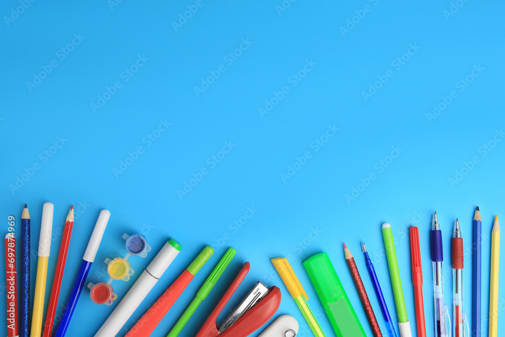 Fototapeta premium Flat lay composition with different school stationery on light blue background, space for text. Back to school