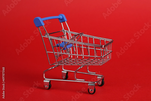 Small metal shopping cart on red background