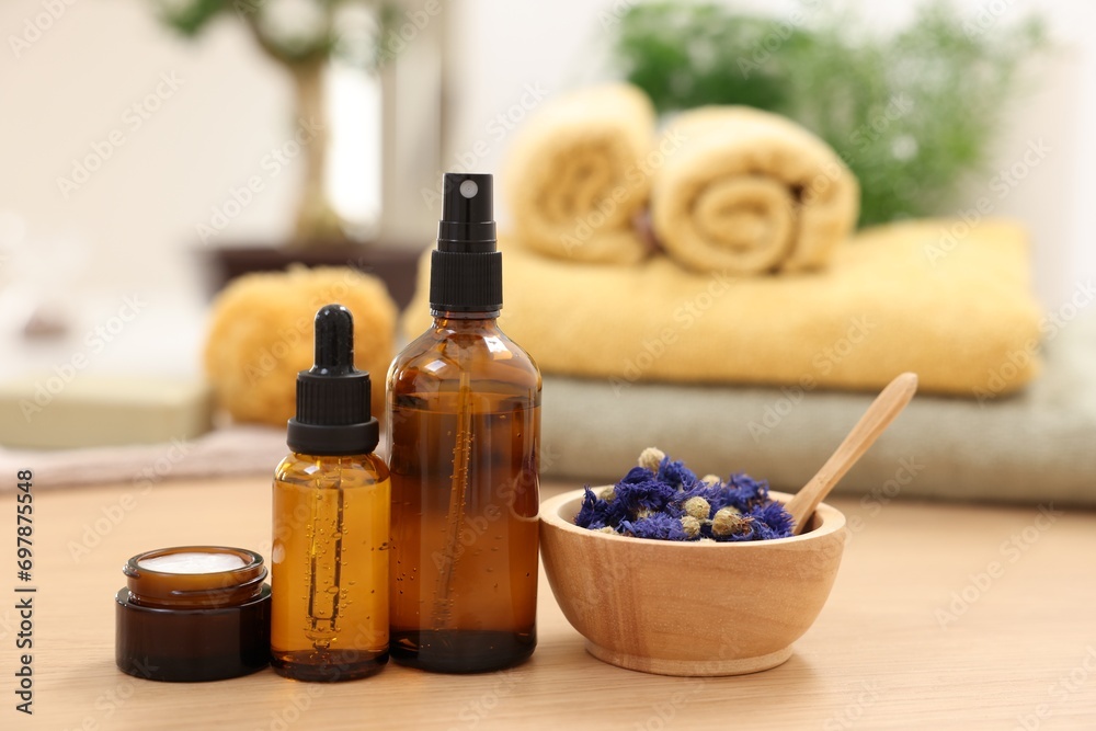 Bottles of essential oils, dry flowers and jar with cream on light wooden table. Spa therapy Bottles of essential oils, dry flowers and jar with cream on light wooden table. Spa therapy
