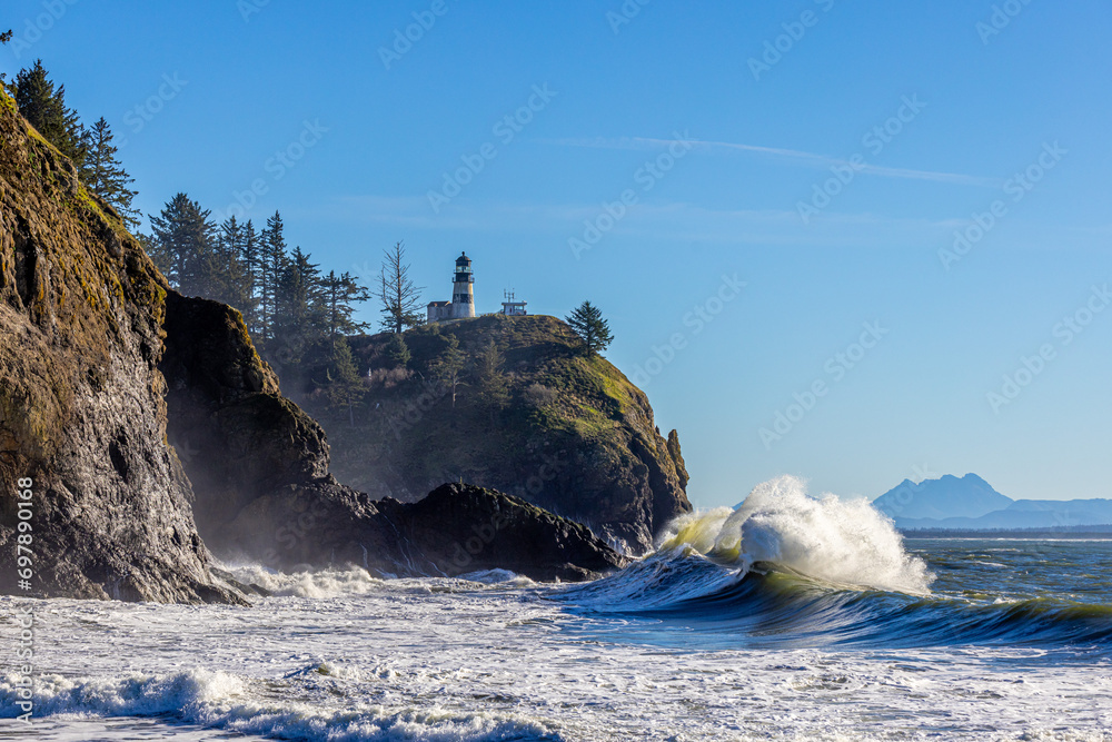 King tides at Cape Disappointment stae part. Large waves crashing on a cliff with a lighthouse