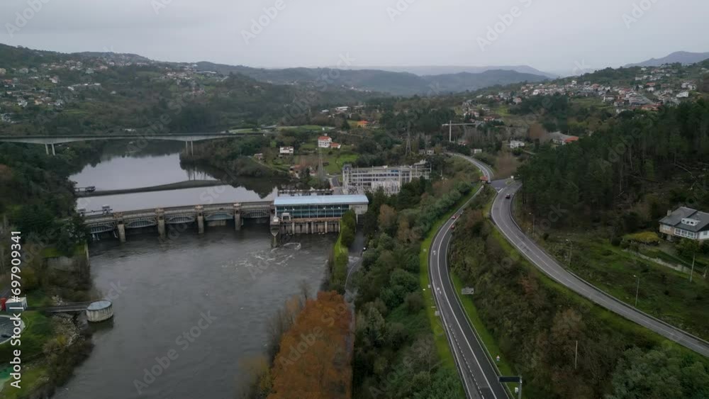 Flyover above highway road lining river by Velle water dam and power plant in Ourense, Galicia, Spain Flyover above highway road lining river by Velle water dam and power plant in Ourense, Galicia, Spain