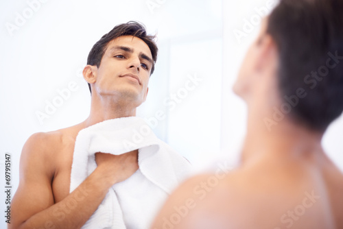 Man, hygiene and towel after washing face in mirror, cleaning and skincare or beauty. Male person, bathroom and wellness in morning routine, reflection and grooming or self care and basin at home photo