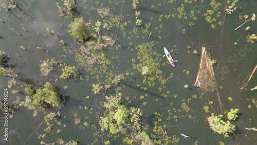 The video shows footage from a drone capturing a kayaker paddling in a serene and clear natural reservoir in Thailand. The atmosphere is peaceful and the water is crystal clear