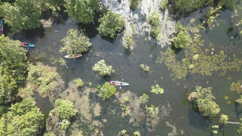 The video shows footage from a drone capturing a kayaker paddling in a serene and clear natural reservoir in Thailand. The atmosphere is peaceful and the water is crystal clear