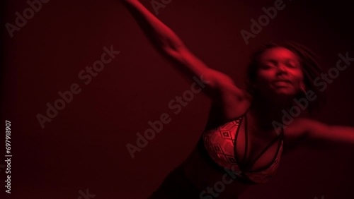  Black woman dancer with a vibrant expression performs dancehall under red lights