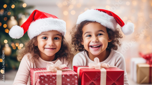 Two little sisters with Santa hats sharing presents and joy during Christmas festivities.