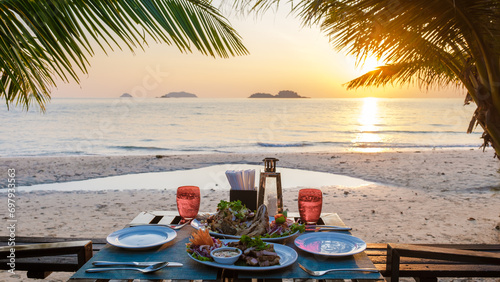 Fototapeta Naklejka Na Ścianę i Meble -  dinner table on the beach at sunset on the Island of Koh Chang Thailand. dinner table with seafood