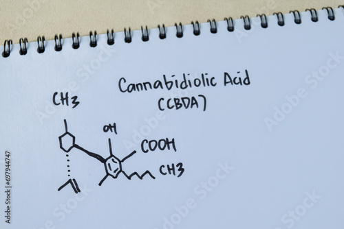 Cannabidiolic Acid (CBDA) molecule written on the book. Structural chemical formula. Education concept photo