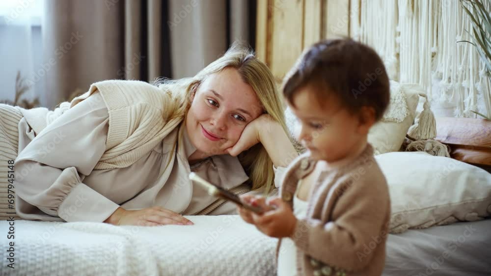 Mother using phone to play cartoon movie to make little baby Mother using phone to play cartoon movie to make little baby