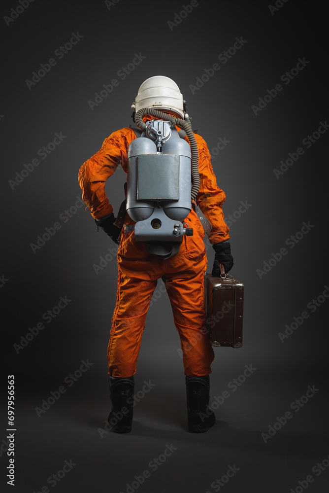 Fototapeta premium Astronaut is standing in the space suit and helmet on the gray background. Back view.