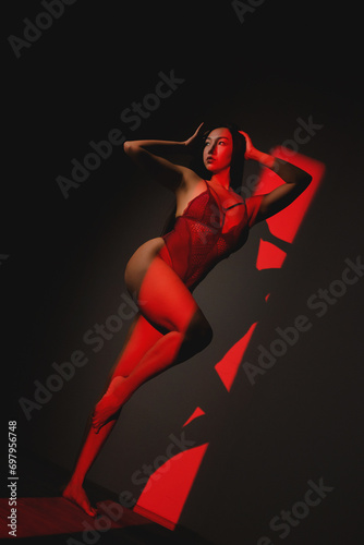 Beautiful asian girl in lingerie posing in the red lights. Beauty and fashion concept.