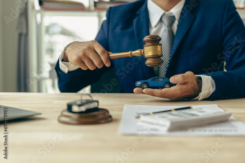 Lawyer, judge's gavel and miniature car as symbols of auction or court action against driver who got into an accident and received car insurance money on the table. Close-up view.