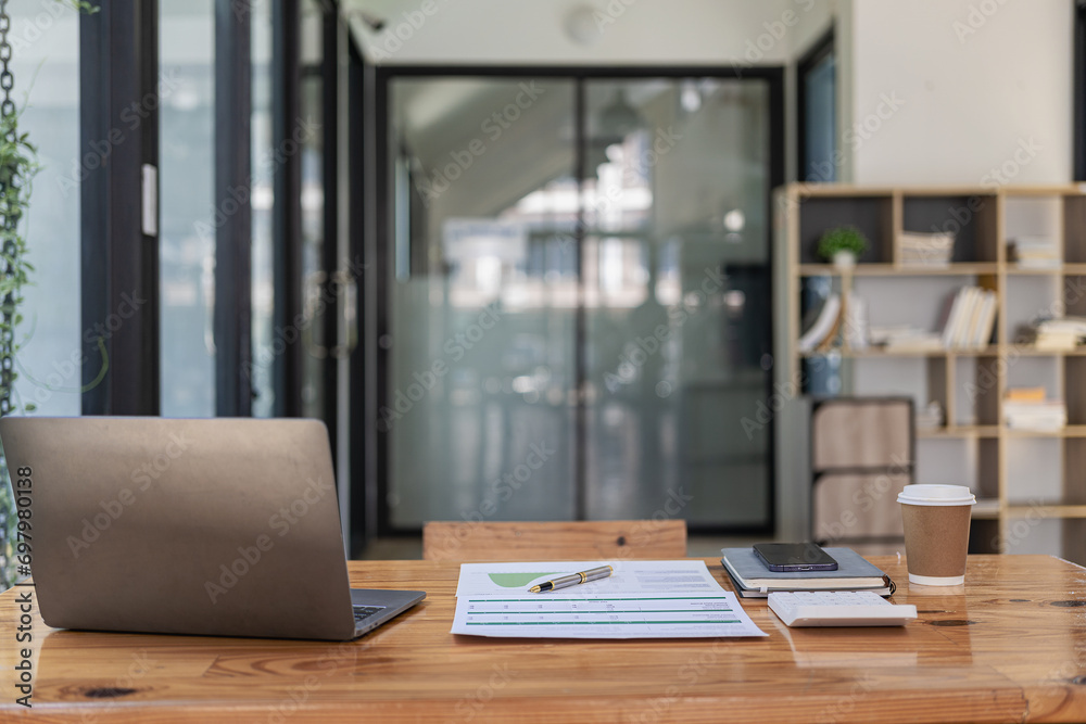 Laptop and financial graph documents on businessman's desk with wooden toys following steps of increasing graph. Ideas for the process of successful business growth. Laptop and financial graph documents on businessman's desk with wooden toys following steps of increasing graph. Ideas for the process of successful business growth.