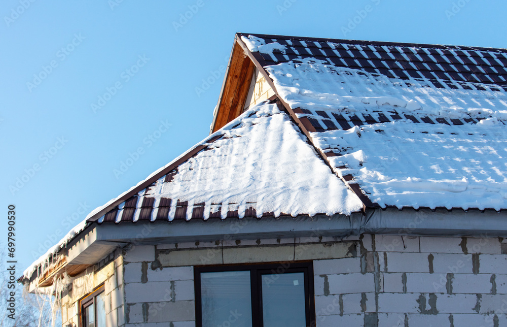 Roof of a house covered in snow against a blue sky