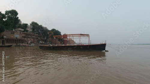 Cinematic sunset scenic boat pan right Ancient Holy city Varanasi India Ganges River canal boat cruise Northern State people at Ghat Pradesh Province landscape gray cloudy photo