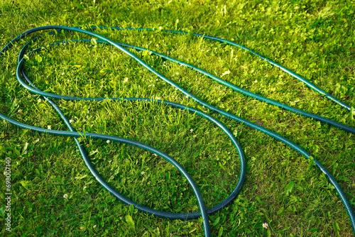 Garden hose lying on green grass photo