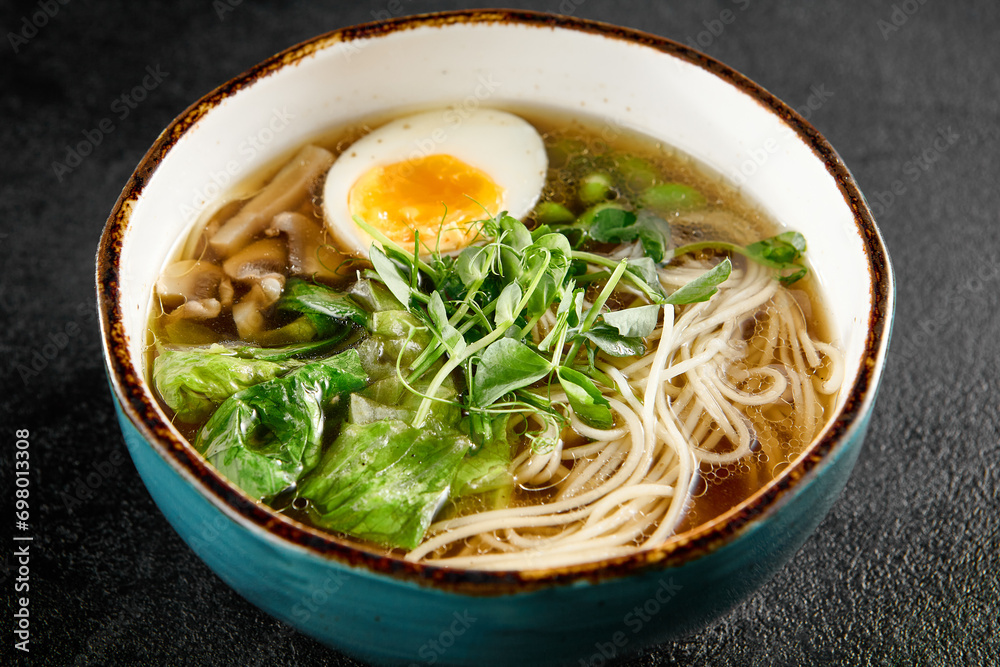Traditional ramen with egg, greens, and mushrooms in a blue bowl