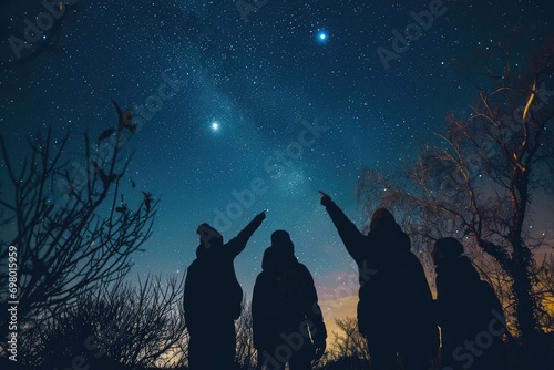Group Of Friends Stargazes And Points At Constellations In Dark Sky Park