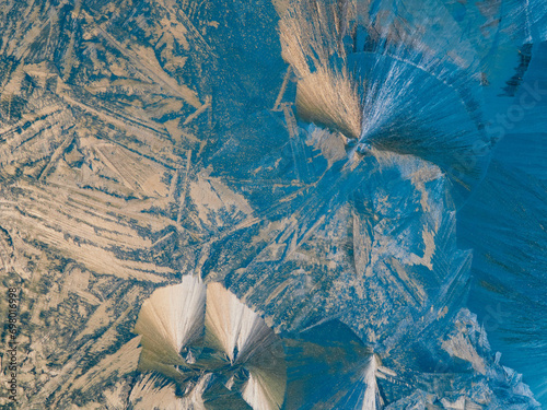 Beautiful ice pattern and sunlight close up on window glass early in the morning, natural winter background