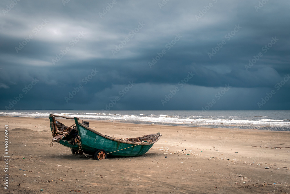 Old wooden fishing boat on a beach against a backdrop of tumultuous grey clouds