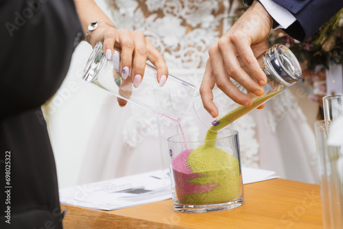 The bride and groom pouring colorful sands of different colors into the glass vase at the marriage unity ceremony. sand ceremony