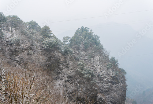 Ancient buildings in China's Wudang Mountains are elegantly decorated with a layer of snow, presenting a harmonious blend of nature and architecture. photo