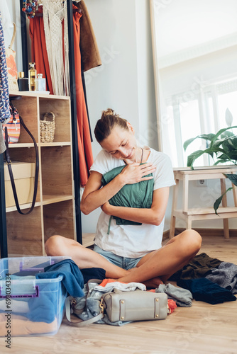 Woman shopaholic sorting through clothes in the wardrobe.