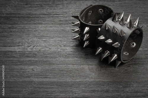Black studded leather bracelet on the black wooden table background close up.