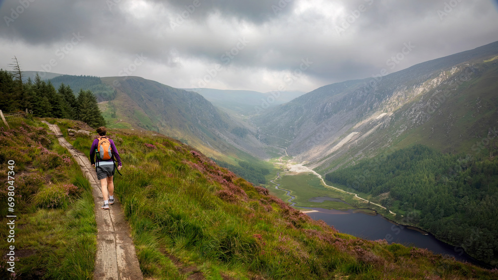 Hiker on the Spinc Trail under a moody sky in Glendalough, County Wicklow, Ireland