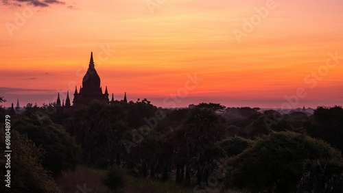 Buddhist temple silhouetted against a beautiful sunset sky over a rural area in Myanmar