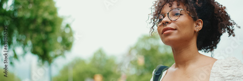 Young woman in glasses walks down the streel. Girl goes on the street in urban background photo