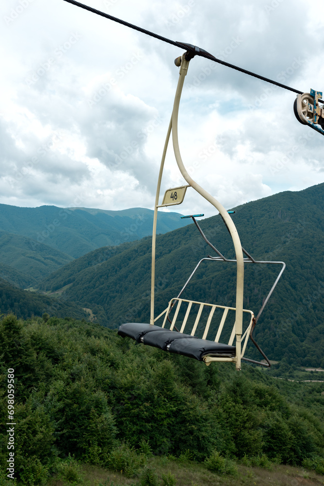 Empty old cable car cabin, cableway in hills of Carpathian mountains, Ukraine. Aerial view, summer green landscape with mountains, pine trees and cloudy sky Empty old cable car cabin, cableway in hills of Carpathian mountains, Ukraine. Aerial view, summer green landscape with mountains, pine trees and cloudy sky