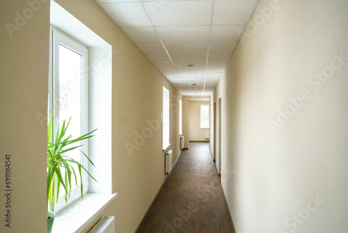 A long empty corridor in an office building. A new modern heating radiator on a white wall. Large double-glazed windows in a modern building.
