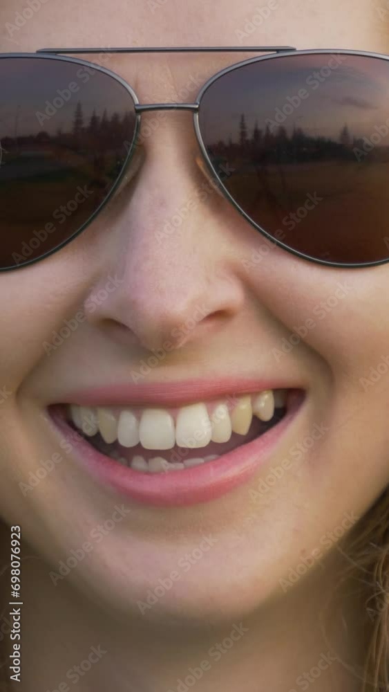 Young caucasian woman in sunglasses is smiling and laughing in park. Close up shot. Vertical Video Young caucasian woman in sunglasses is smiling and laughing in park. Close up shot. Vertical Video