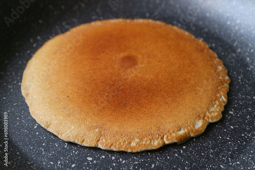Closeup of an almost ready fried plain pancake in fry pan photo