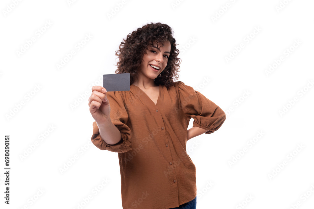 © Ivan Traimak - young fashionista curly brunette woman dressed in a stylish brown blouse shows a plastic card