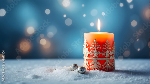 Decorated and Lit Christmas Candle on Snowy Surface and Blurred Background in Blue Tone