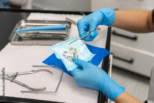 Close-up of the dentist's hand opens a sterile package with clamps. Dental instruments are on the table in the dentist's office. photo