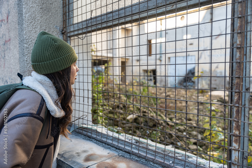 Young sad homeless woman depressed and abandoned standing on the street near ex building which is demolished for new apartments. Female mental illness suffering from depression anxiety after eviction