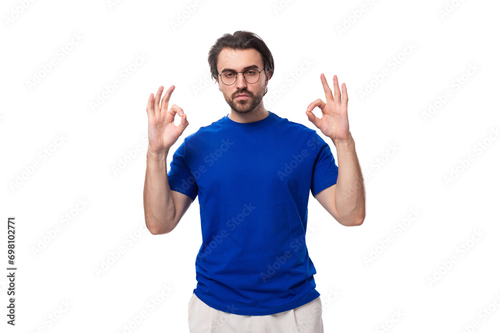 portrait of a young caucasian brunette man with a stylish hairstyle and beard in a blue t-shirt with space for logo printing portrait of a young caucasian brunette man with a stylish hairstyle and beard in a blue t-shirt with space for logo printing