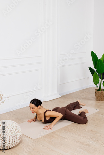 A woman wears dark sportswear, practices asana, and sports exercises for a flexible body. Training for beginners. Concept of sportswear and flexible healthy body.