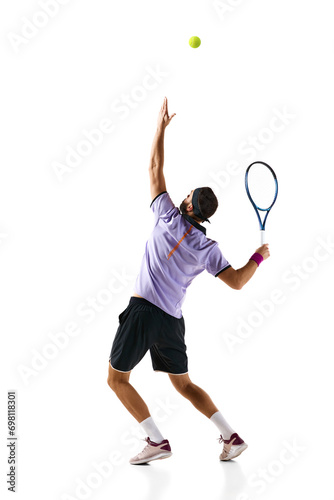 Full-length dynamic image of young man, tennis player in motion, serving ball with racket isolated over white background. Concept of professional sport, movement, competition, action. Ad © master1305