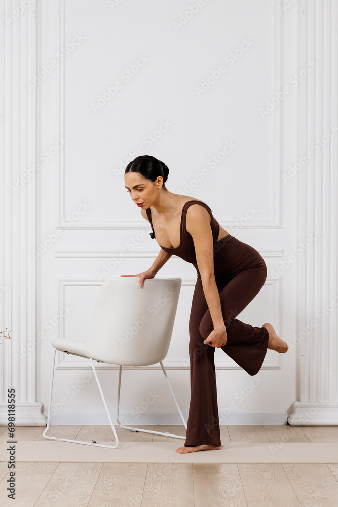 A woman wears dark sportswear, practices asana, and sports exercises for a flexible body. Training for beginners. Concept of sportswear and flexible healthy body. A woman wears dark sportswear, practices asana, and sports exercises for a flexible body. Training for beginners. Concept of sportswear and flexible healthy body.