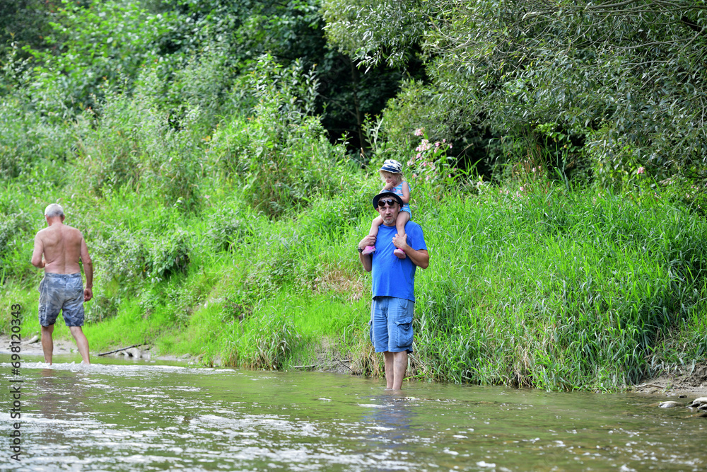Shallow river and tourists going for a picnic on the beach by the river