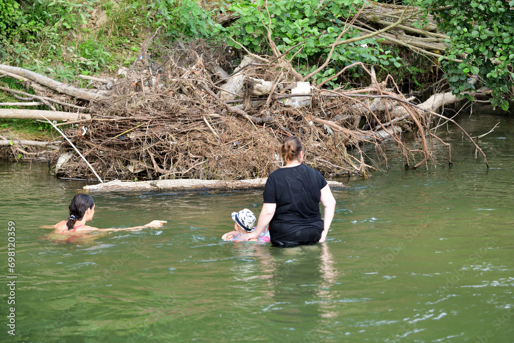 A little girl learns to swim in a river using a lifebuoy