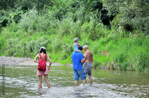 Obraz na płótnie Shallow river and tourists going for a picnic on the beach by the river w salonie