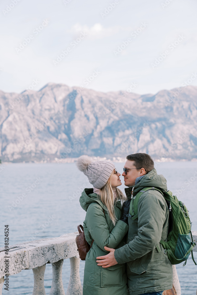 Man and woman almost kiss near the stone balustrade over the sea